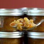 green tomato chutney in jars with spoon of chutney in foreground