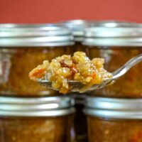 Green tomato chutney in jars and on a spoon.