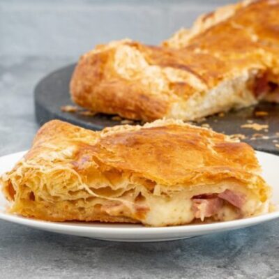 a slice of ham, gruyere, and fig tart on a plate