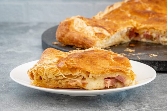 a slice of ham, gruyere, and fig tart on a plate