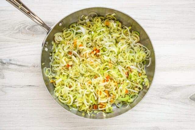 Sautéed leeks and vegetables in a skillet.