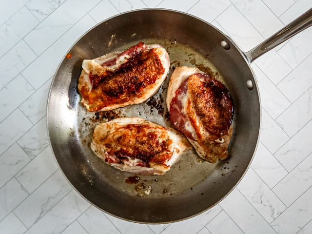 Searing the stuffed chicken breasts.