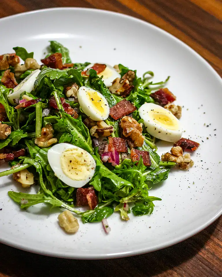 Grilled sausage and bacon salad with hard-boiled eggs and greens.