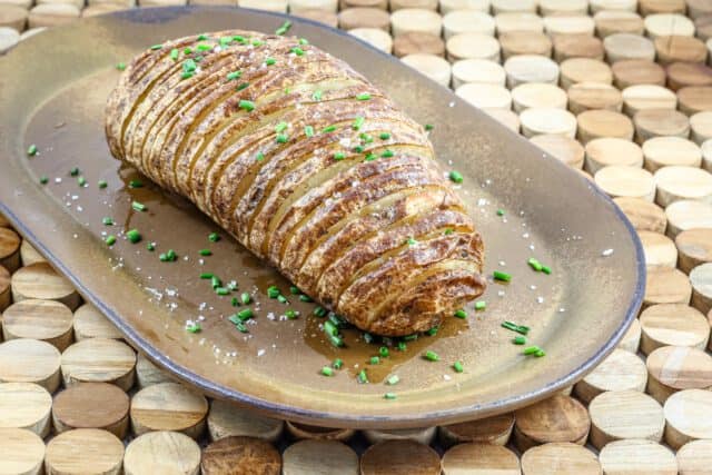 Golden brown cannoli with green sprinkles on a decorative plate.