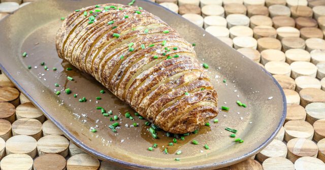 Baked Hasselback potatoes garnished with chives.
