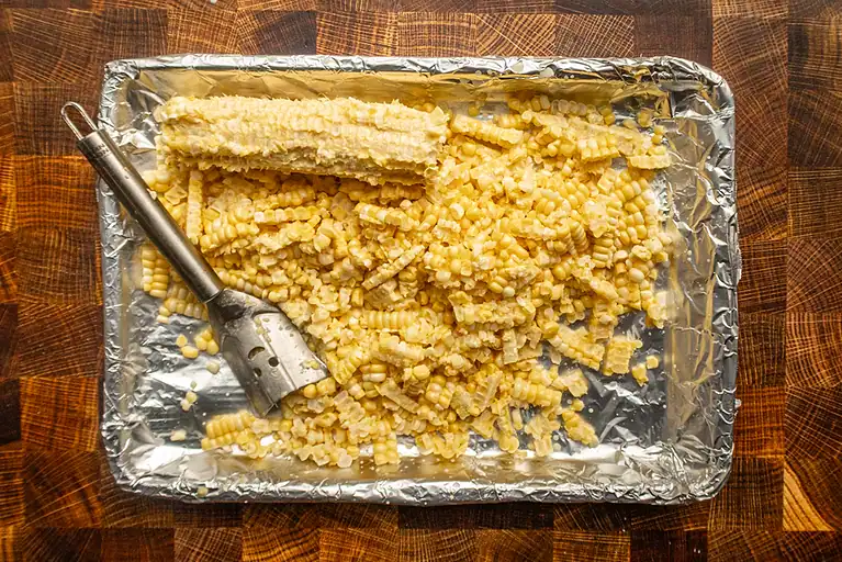Cooked, shredded pasta with cheese on foil-lined tray.