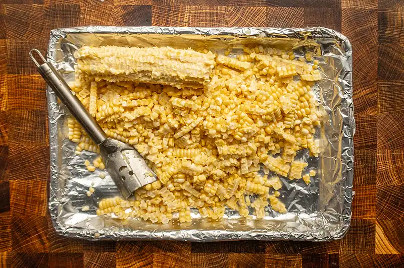 Cooked, shredded pasta with cheese on foil-lined tray.