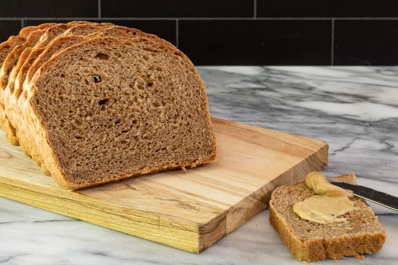 Sliced homemade pumpernickel bread on a cutting board