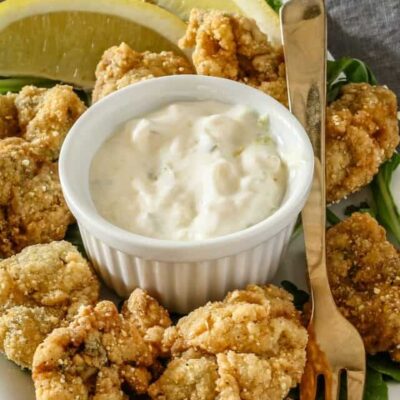 Crispy fried chicken bites with creamy dipping sauce and lemon slices.