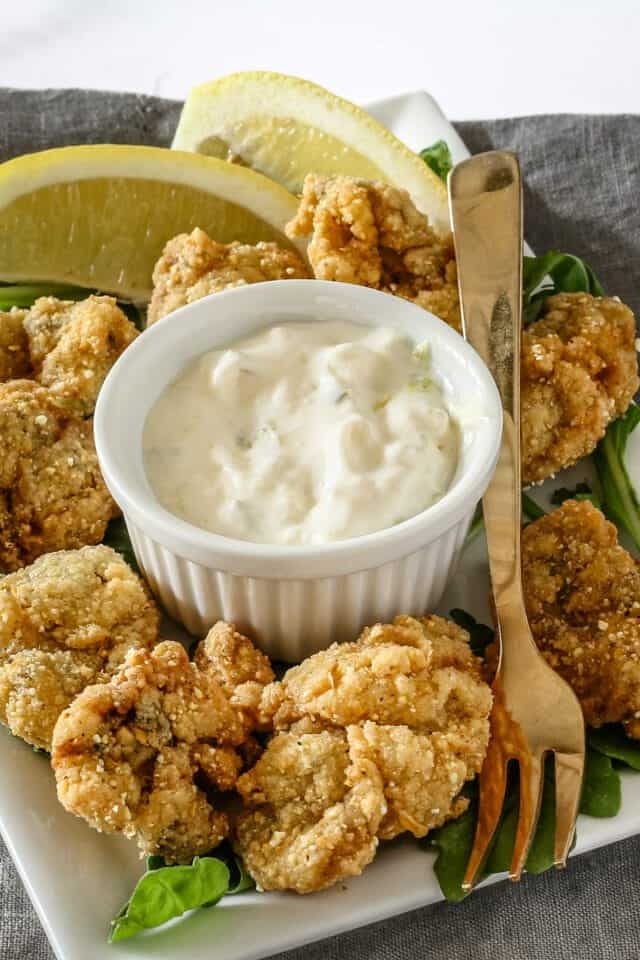 Crispy fried chicken bites with creamy dipping sauce and lemon slices.