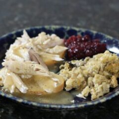 a hot turkey sandwich with leftover stuffing, cranberry sauce, and gravy