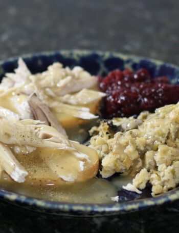 a hot turkey sandwich with leftover stuffing, cranberry sauce, and gravy