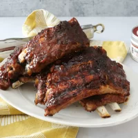 Baked pork ribs with barbecue sauce on a white plate.