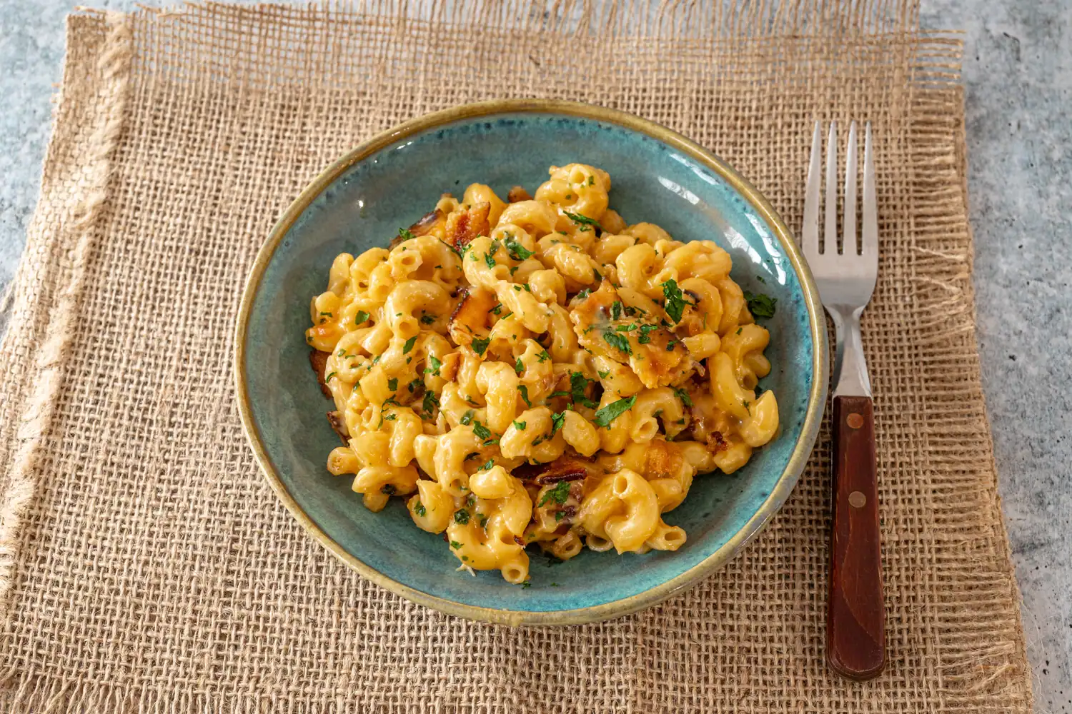 Bacon macaroni and cheese in a bowl with parsley garnish.
