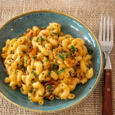 Creamy macaroni and cheese with chopped herbs on top.