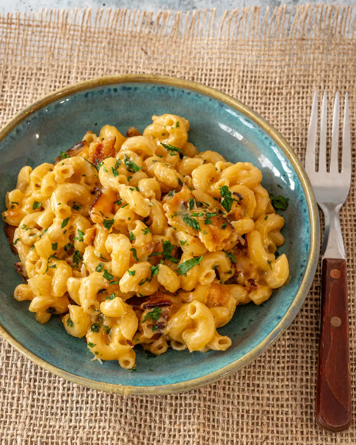 Creamy macaroni and cheese with chopped herbs on top.