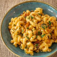 Bacon macaroni and cheese in a bowl with parsley garnish.