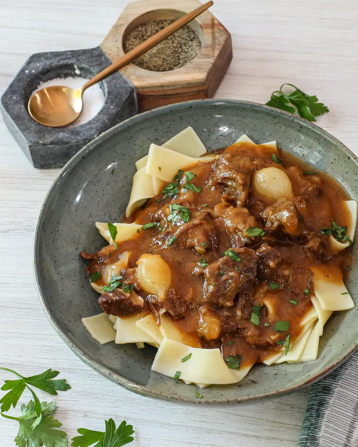 Beef stew with potatoes and noodles in a rustic bowl.
