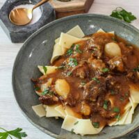 Instant Pot beef and beer stew (carbonnade) in a bowl with pappardelle pasta.