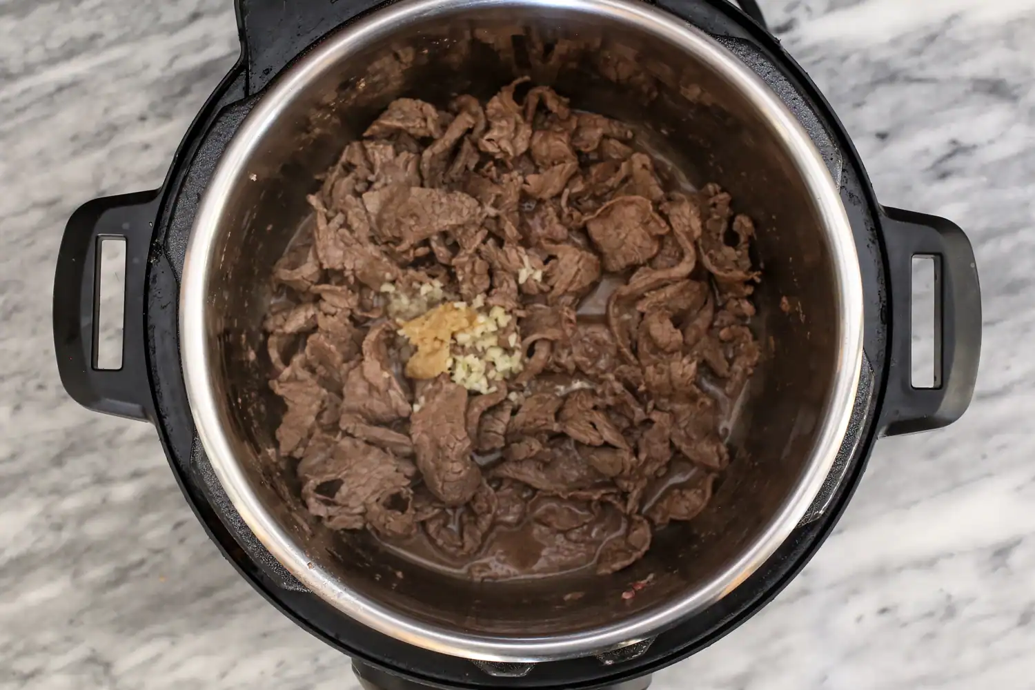 Beef combined with seasonings in the Instant Pot.