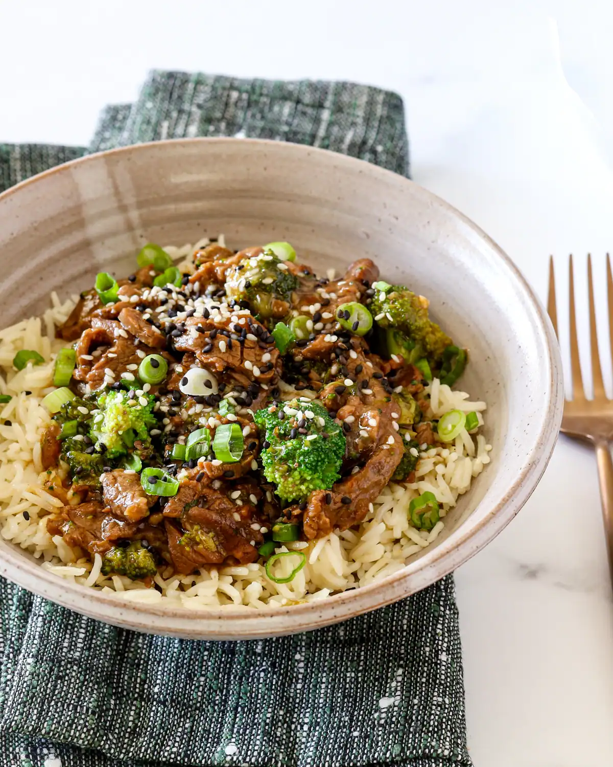 Steamed rice topped with stir-fried broccoli, beef, and sesame seeds.