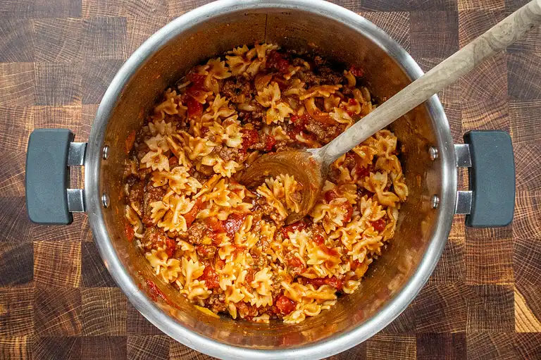Cooked beef and pasta chili mixture in a stainless steel pot.