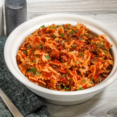 Savory pasta with ground beef and tomato sauce garnished with fresh herbs.