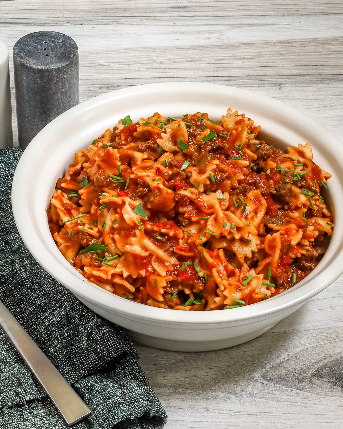 Savory pasta with ground beef and tomato sauce garnished with fresh herbs.