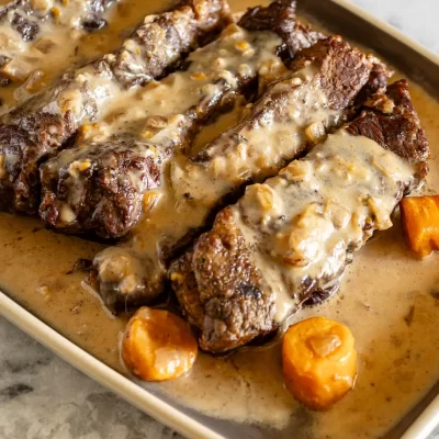 Slow-cooked beef ribs with creamy gravy and carrots.
