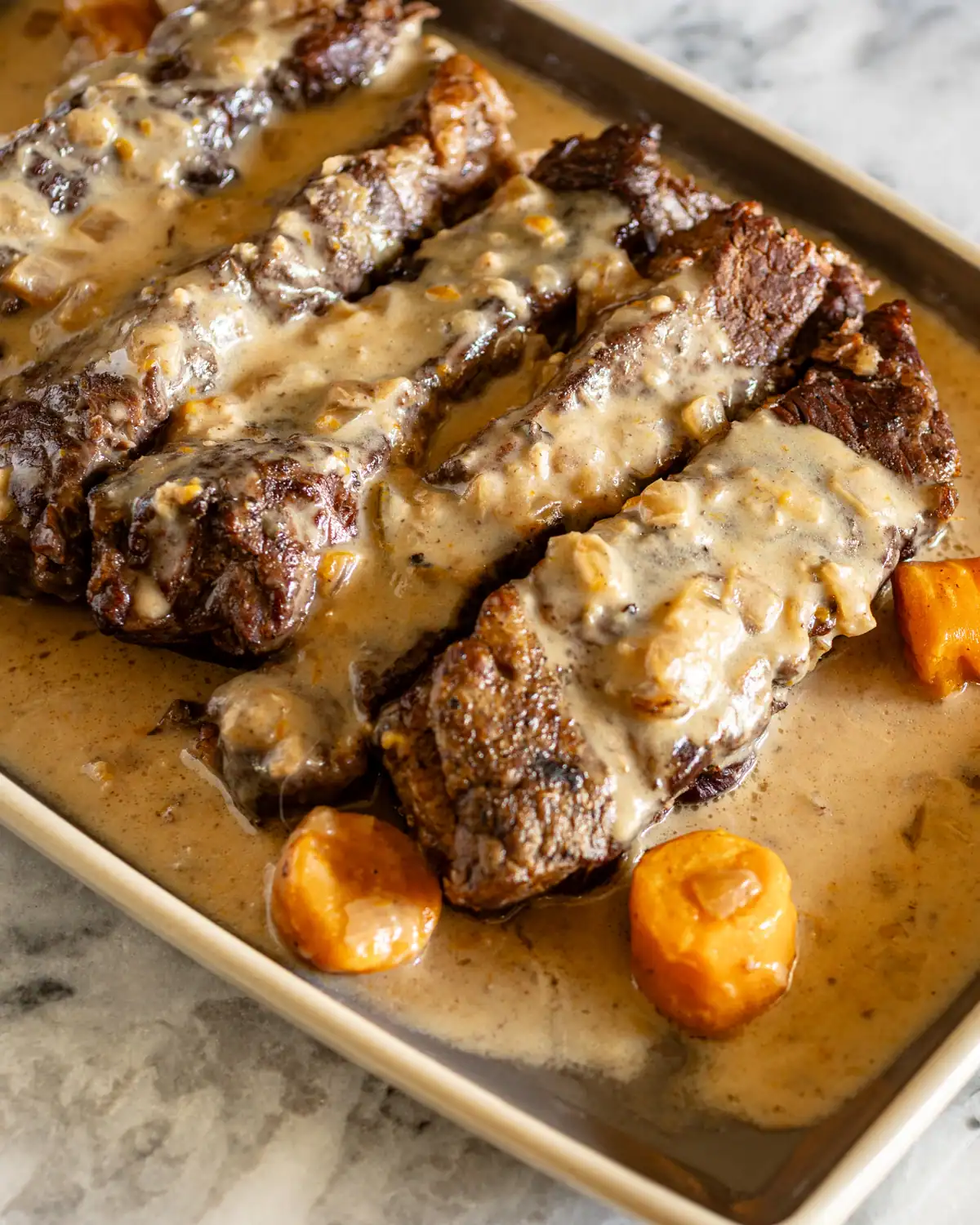 Slow-cooked beef ribs with creamy gravy and carrots.