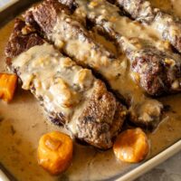 Instant Pot beef short ribs on a serving tray with carrots and sauce.