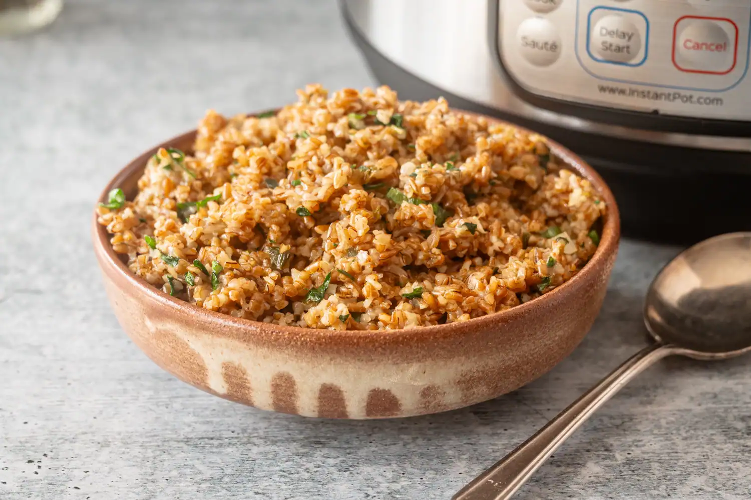 A bowl with bulgur pilaf, cooked in the Instant Pot pressure cooker with green onions, garlic, and chicken broth.
