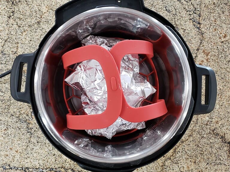 Cooker with aluminum foil-lined basket and a pink silicone egg steamer insert.