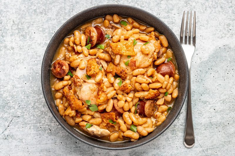 Bowl of instant pot cassoulet made with great northern beans, chicken thighs, bacon, and sausage.