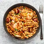 Bowl of white bean and chicken stew with sausage and herbs.
