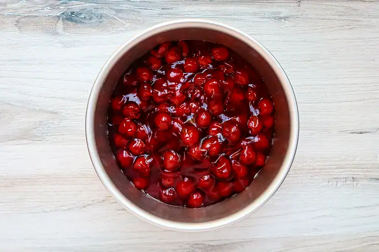 Bowl of fresh red cherries soaking in juice.
