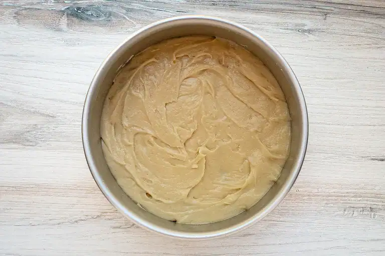 Creamy batter in a round baking pan ready for baking.