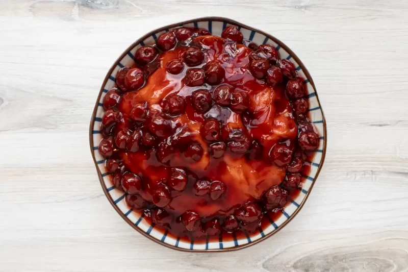Sweet cherry topped dessert in a striped bowl.