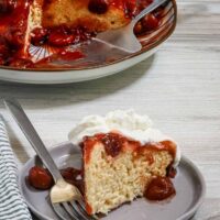 An Instant Pot (instapot) cherry upside-down cake, sliced and served with a whipped cream topping.