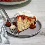 Soft vanilla cake with cherry topping and whipped cream.