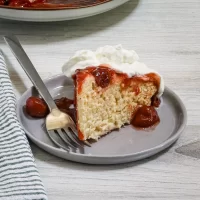 Soft vanilla cake with cherry topping and whipped cream.