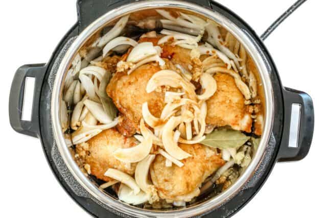 Golden fried chicken pieces with onions in a slow cooker.