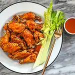 Fried chicken wings with celery sticks and dipping sauce.