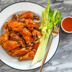 Crispy buffalo chicken wings with celery sticks and dipping sauce.