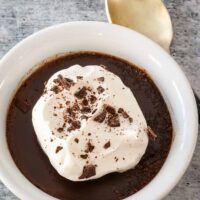 Closeup of a serving of Instant Pot pot de crème with whipped cream and chocolate shavings.