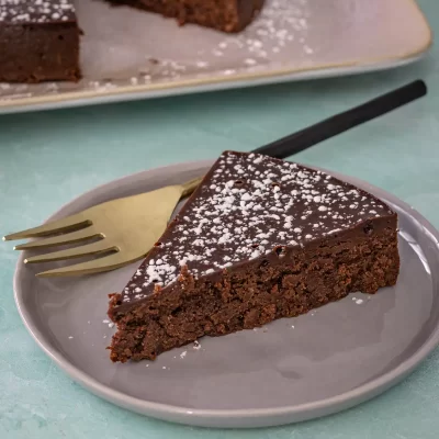 Rich chocolate brownie slice with powdered sugar on top.