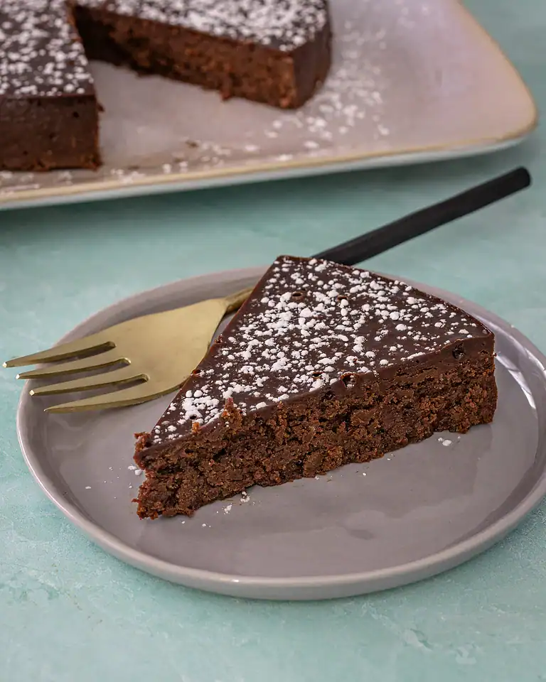 Rich chocolate brownie slice with powdered sugar on top.