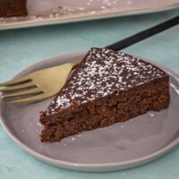 A slice of Instant Pot chocolate truffle cake on a plate with powdered sugar sprinkle.