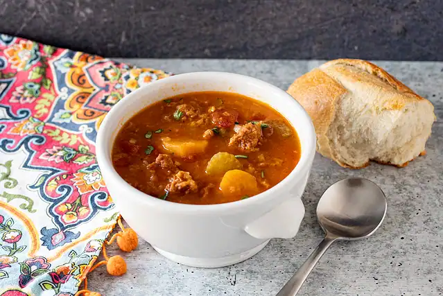 Instant Pot chorizo and lentil soup in a bowl with crusty bread on the side.