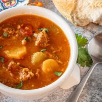 Instant Pot chorizo and lentil soup in a bowl with crusty bread on the side.